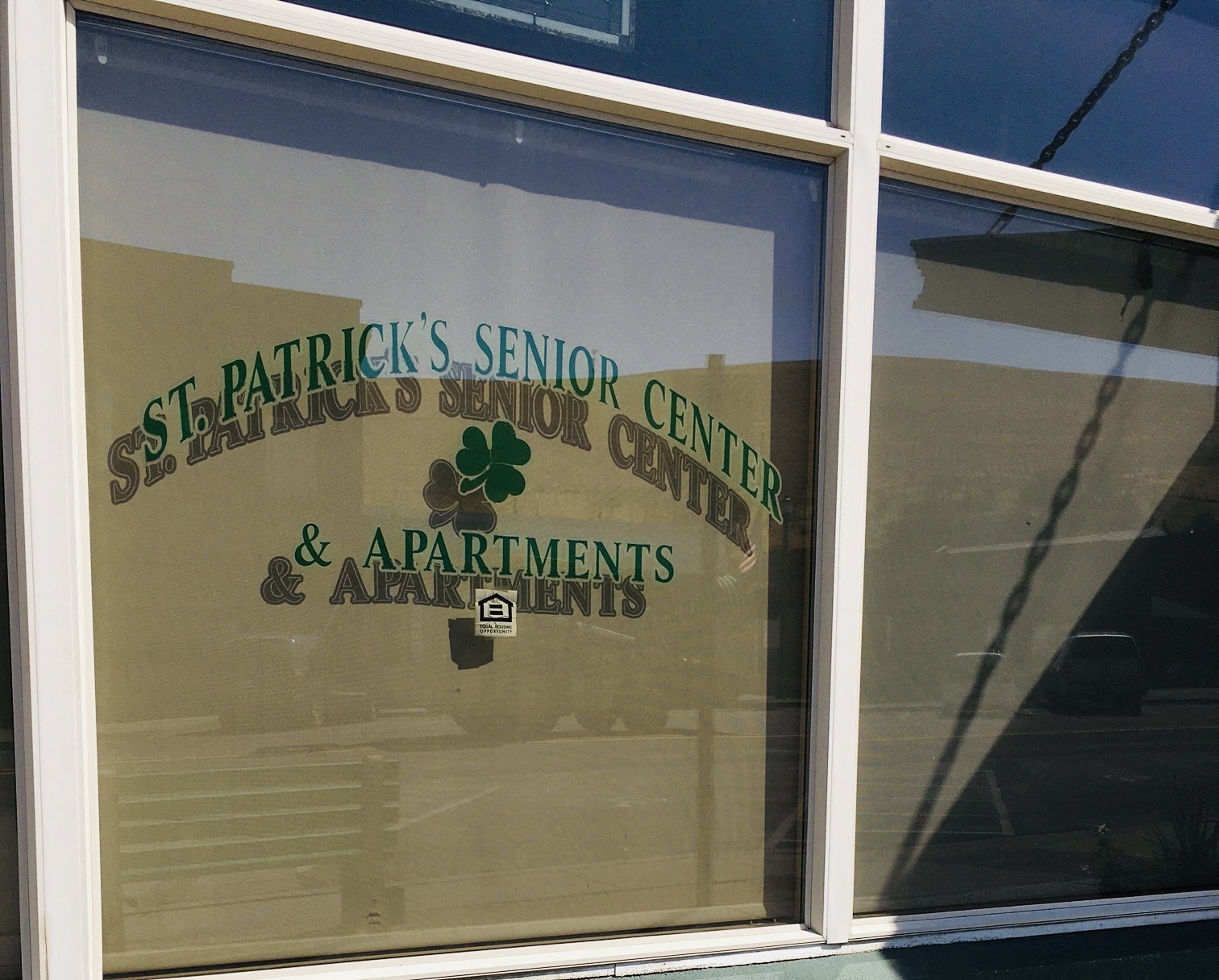 the front window of the senior center with a reflection of a parking lot